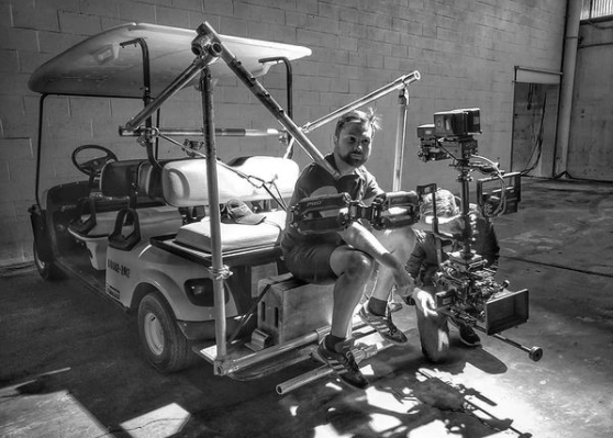 Nick Schwyter seated beside a stabilized camera rig mounted to a production cart for Boosted.